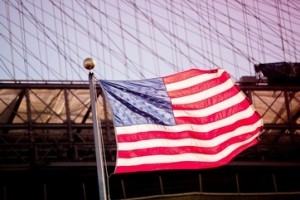 American flag waving by urban bridge